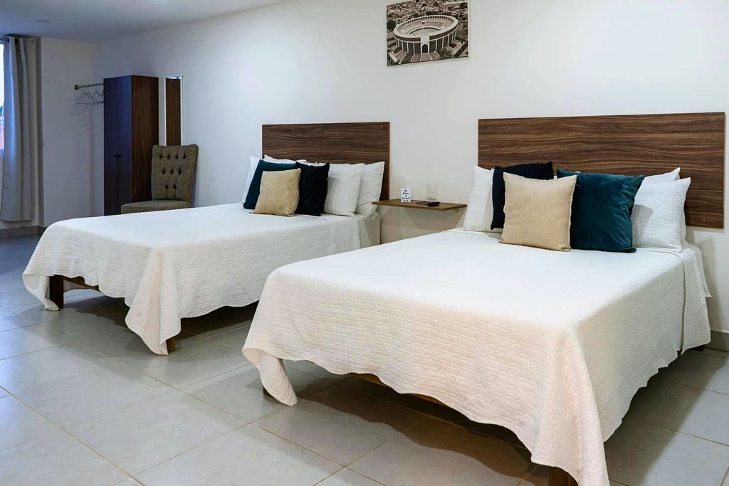 Habitación doble con dos camas, cabecera de madera, sillón y clóset