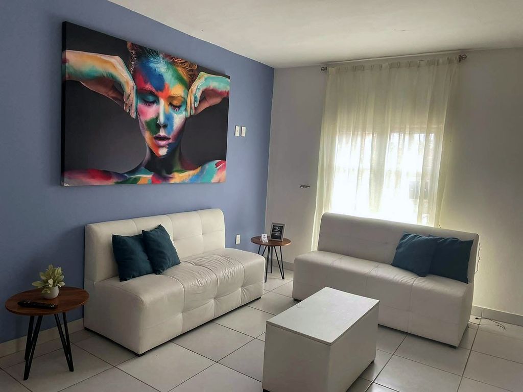 Sala con dos sillones blancos y un cuadro grande